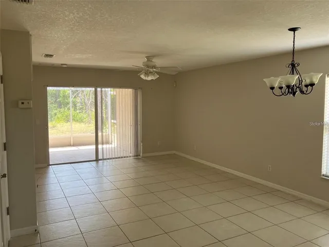 an empty room with windows and ceiling fan