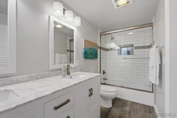 a bathroom with a granite countertop sink a toilet and shower