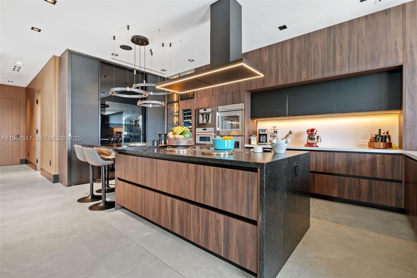 655 Layne Boulevard Hallandale Beach, FL 33009 - Photo 14 of 46 a kitchen with stainless steel appliances kitchen island granite countertop a table chairs in it and wooden floors