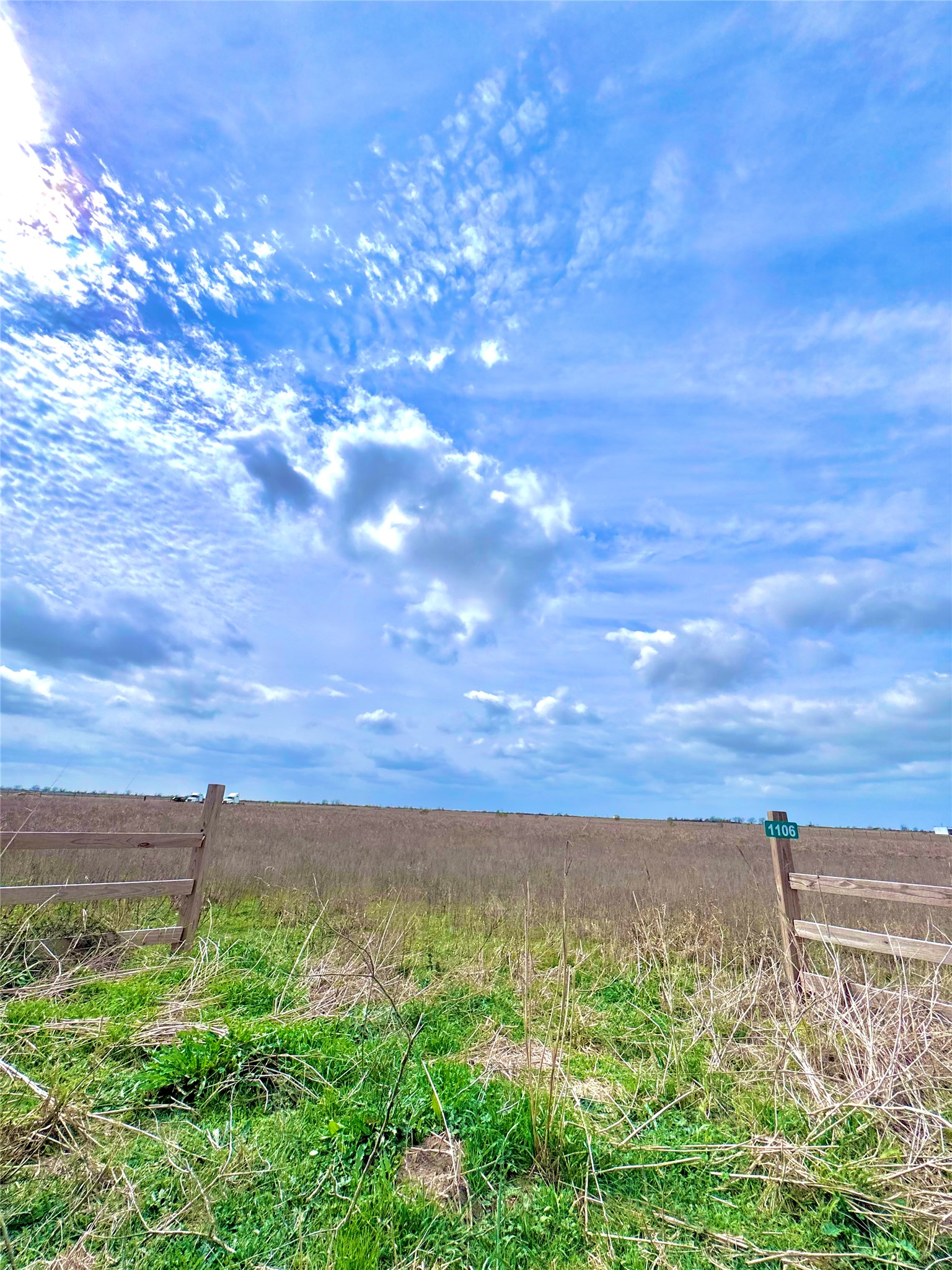 Expansive undeveloped lot featuring a wooden fence and abundant natural vegetation