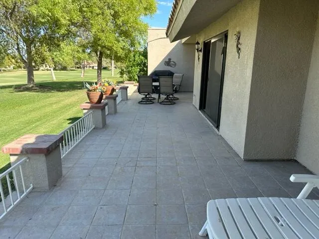 a view of a patio with lawn chairs floor to ceiling window and a yard