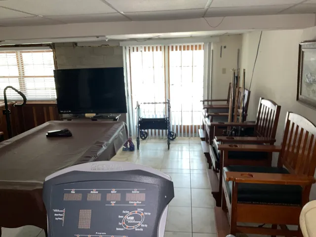 a living room with furniture a flat screen tv and a floor to ceiling window
