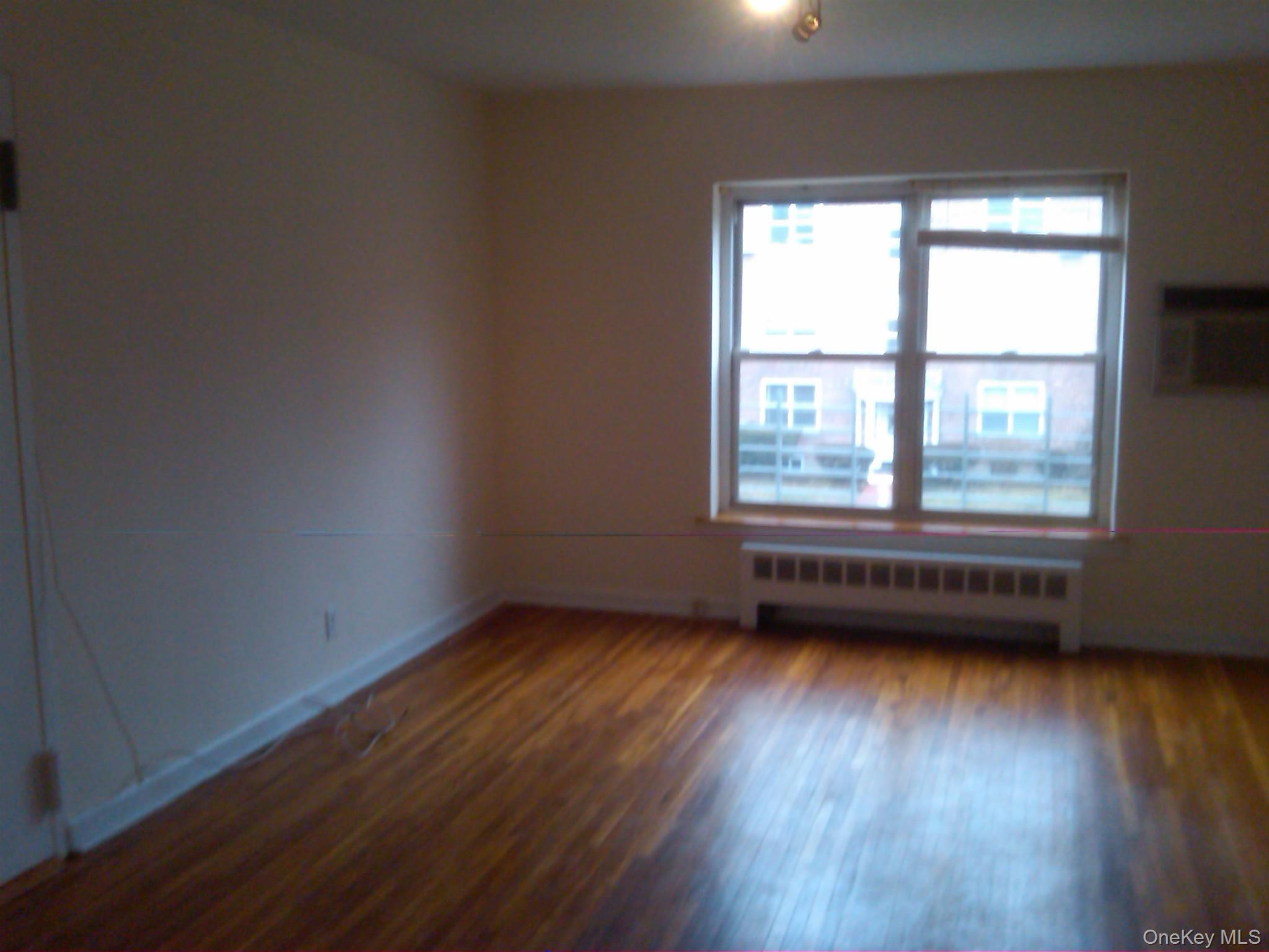 221 Middle Neck Road, Unit H3 Great Neck, NY 11021 - Photo 3 of 9 an empty room with wooden floor and windows