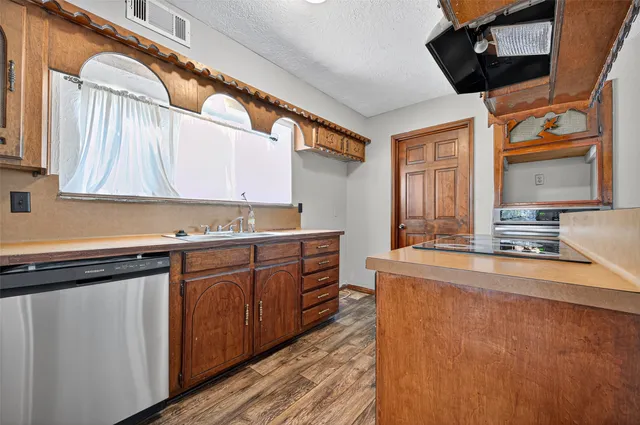 a kitchen with stainless steel appliances granite countertop a sink a stove and a wooden cabinets