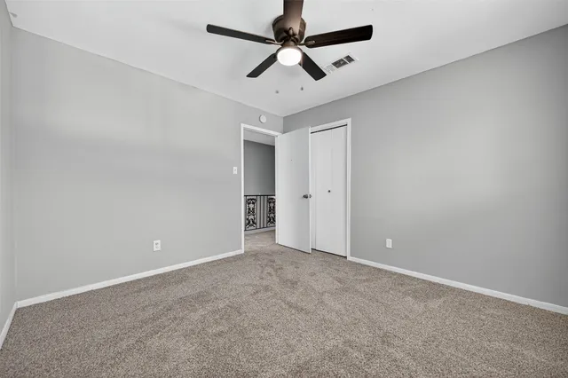 an empty room with windows and a ceiling fan