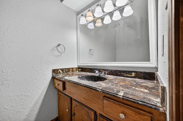 a bathroom with a granite countertop sink and a mirror