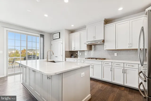 a kitchen with stainless steel appliances granite countertop a stove a sink and white cabinets with wooden floor