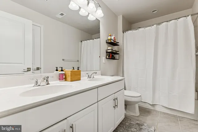 a bathroom with a double vanity sink mirror and toilet
