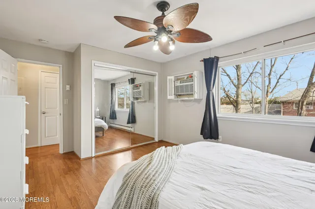 a bedroom with a bed and a large window with wooden floor