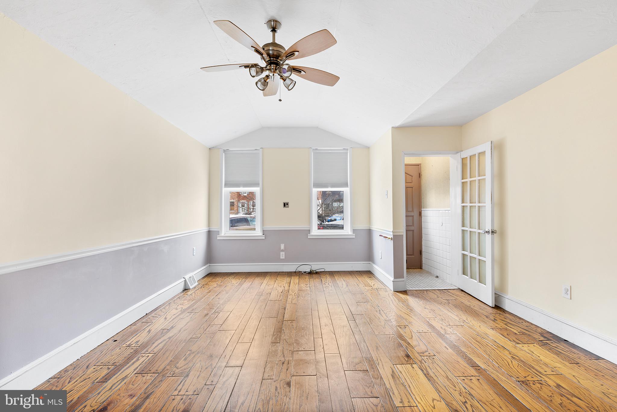 a view of a room with wooden floor and a ceiling fan