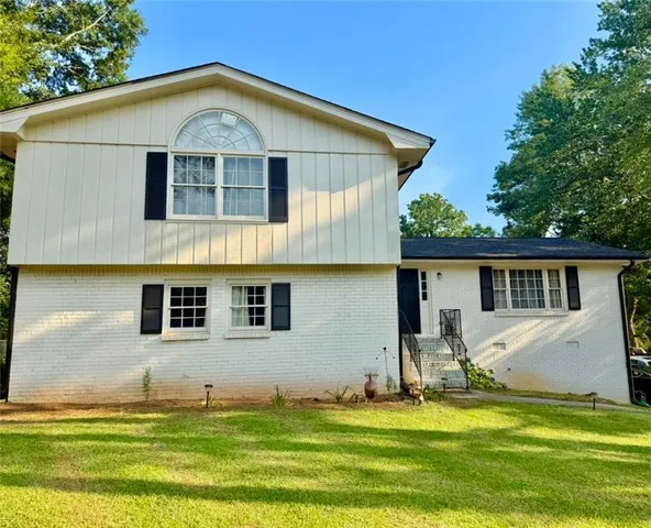 a white house that has a small yard and trees in front of it