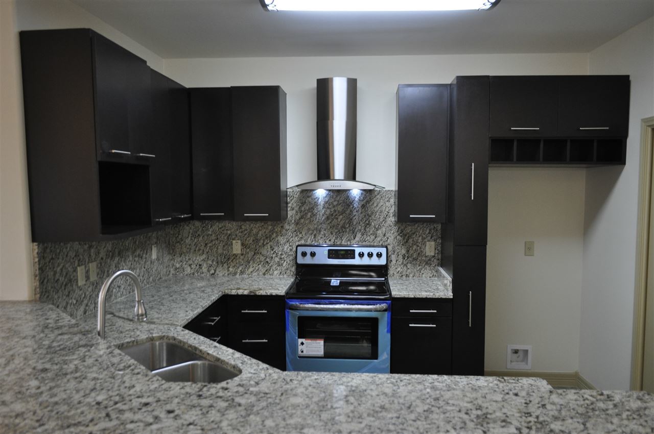 8216 Casa Verde Road, Unit E158 Laredo, TX 78041 - Photo 6 of 20 a kitchen with granite countertop a refrigerator and a stove