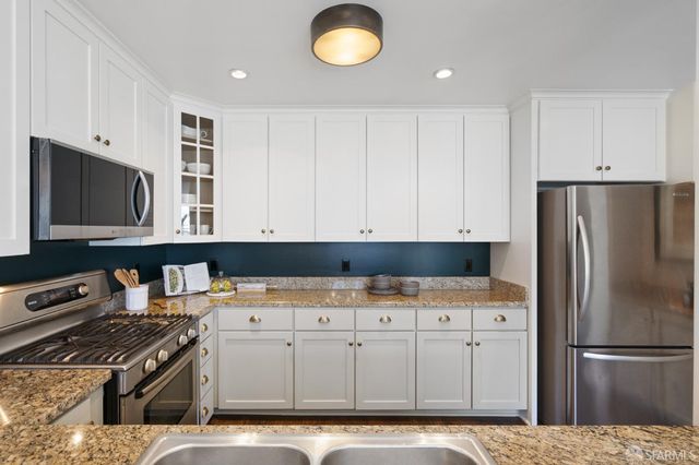 a kitchen with stainless steel appliances granite countertop a stove a sink and a refrigerator