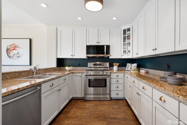 a kitchen with granite countertop a sink stainless steel appliances and cabinets