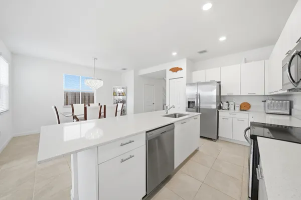 a kitchen with a sink a refrigerator and white cabinets