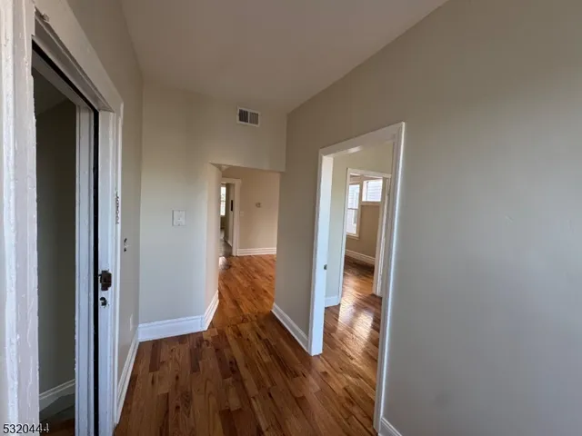 a view of a hallway with wooden floor and staircase