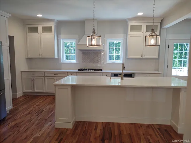 a open kitchen with white cabinets and wooden floor