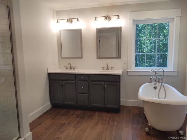a bathroom with a double vanity sink a mirror and a bathtub