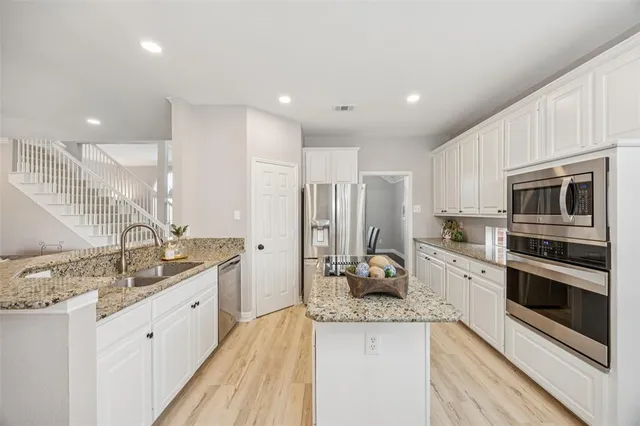 a kitchen with stainless steel appliances kitchen island granite countertop a sink stove and refrigerator