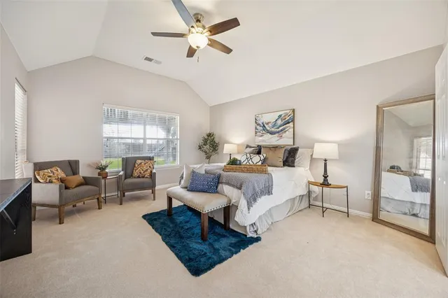a bedroom with a large bed couch and windows