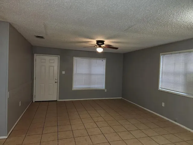 an empty room with windows and fan