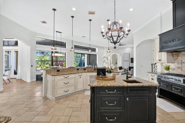 a kitchen with stainless steel appliances kitchen island granite countertop a stove a sink and a flat screen tv