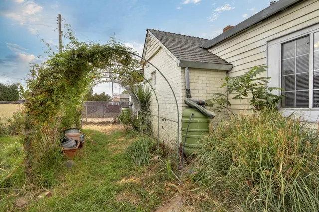 a backyard of a house with table and chairs and potted plants