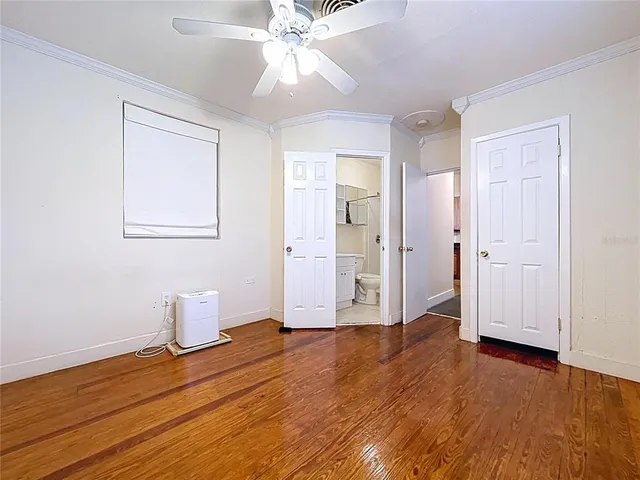 an empty room with wooden floor closet fan and windows