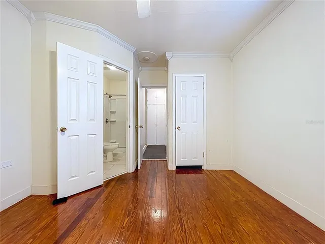 an empty room with wooden floor chandelier fan and windows