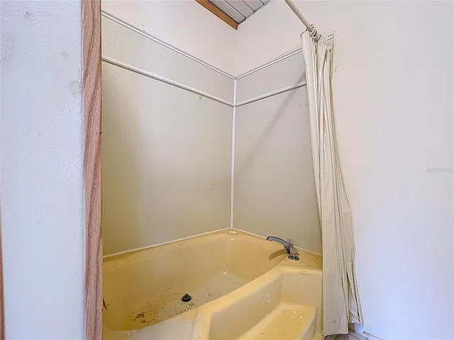 a view of an empty room with window and chandelier fan