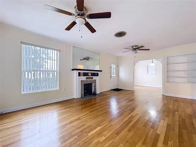 a view of empty room with wooden floor and fan