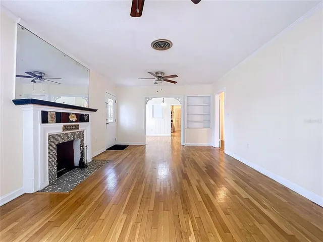 an empty room with wooden floor chandelier fan and windows