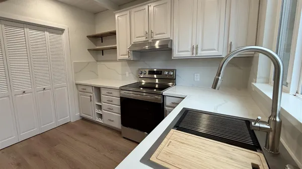 a kitchen with stainless steel appliances kitchen island granite countertop a stove and a wooden cabinets