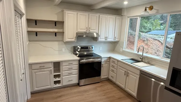a kitchen with stainless steel appliances granite countertop a sink and cabinets with wooden floor