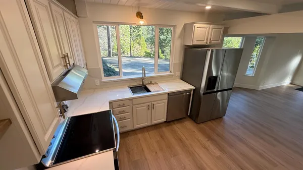 a kitchen with stainless steel appliances granite countertop a refrigerator a sink dishwasher and wooden floor