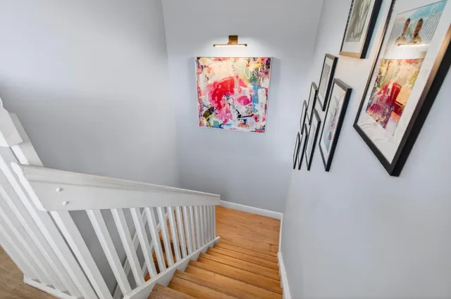 a view of a hallway to a livingroom with wooden floor a ceiling fan and windows