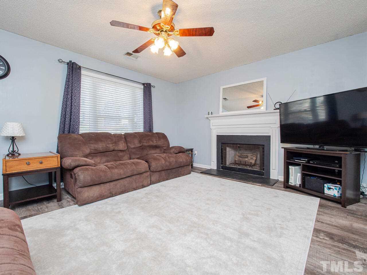 3540 Tunas Street Raleigh, NC 27616 - Photo 5 of 24 a living room with furniture a flat screen tv and a fireplace