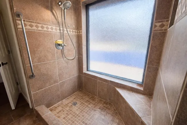 a bathroom with a glass shower door and a window