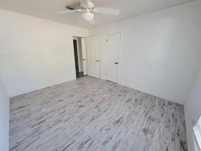 a view of room with wooden floor and ceiling fan