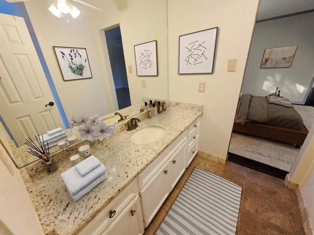 a bathroom with a granite countertop tub sink and mirror