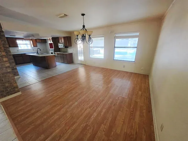 an empty room with wooden floor fireplace and windows
