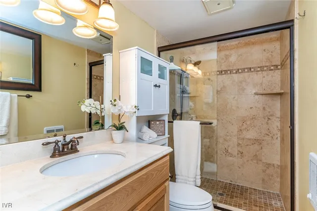 a bathroom with a granite countertop sink a toilet a mirror and shower