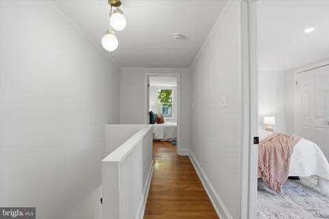 a view of a hallway with wooden floor and a bathroom
