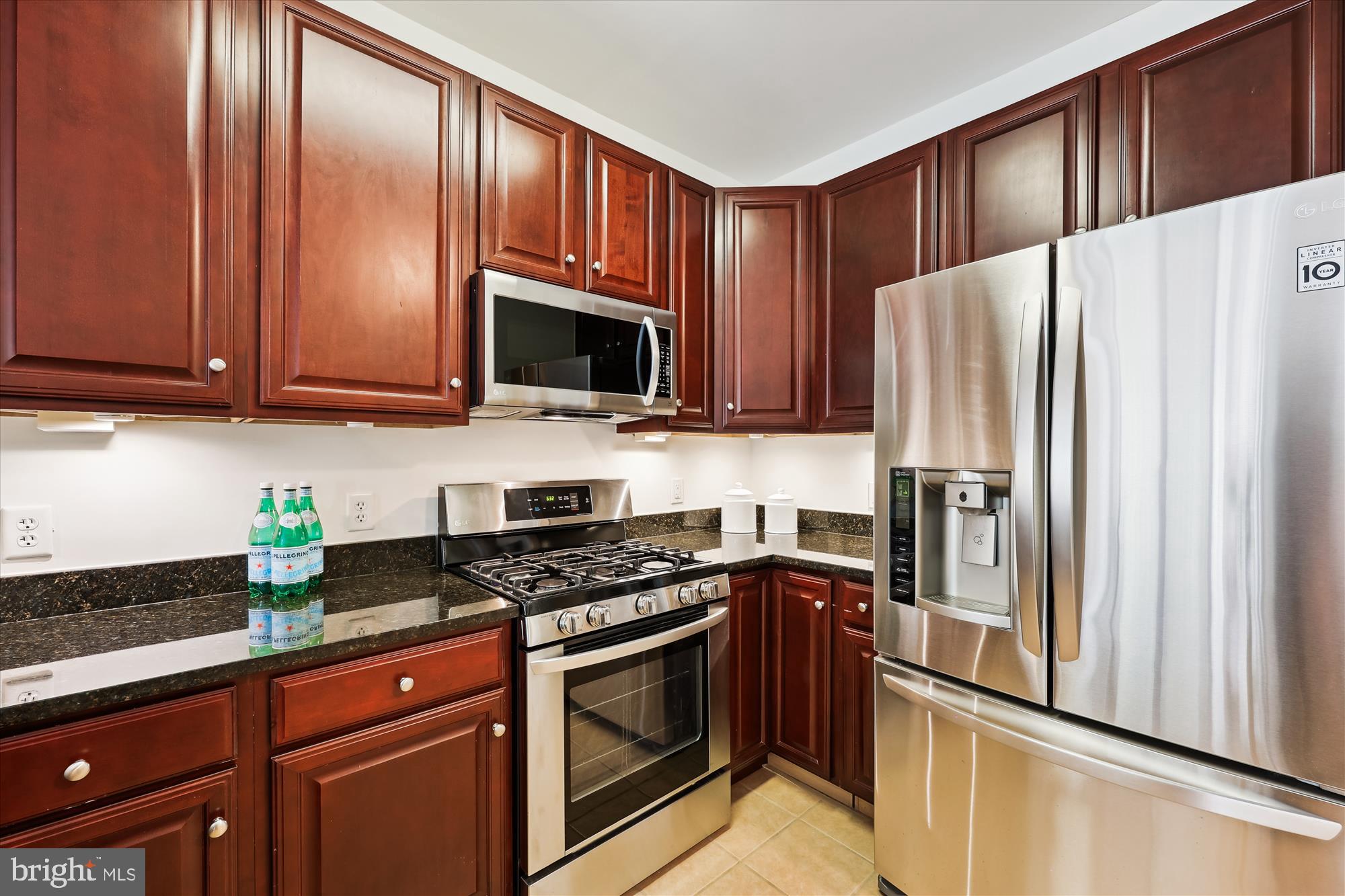 8045 Newell Street, Unit 319 Silver Spring, MD 20910 - Photo 11 of 66 a kitchen with granite countertop wooden cabinets stainless steel appliances and a refrigerator