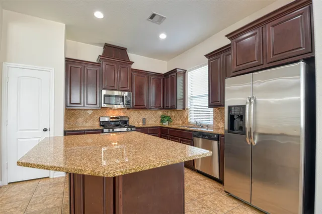 a kitchen with granite countertop a refrigerator a sink and wooden cabinets