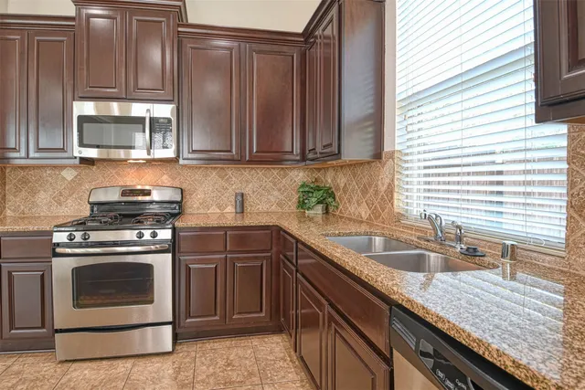 a kitchen with granite countertop a sink stove and cabinets