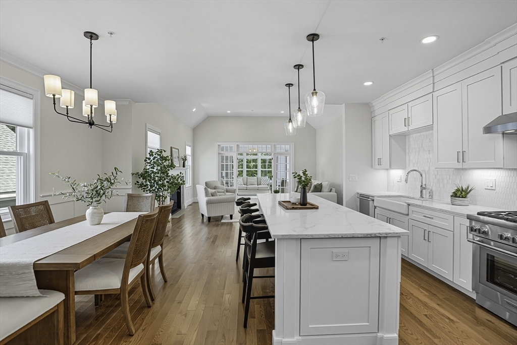 a kitchen with stainless steel appliances kitchen island a table chairs in it and white cabinets