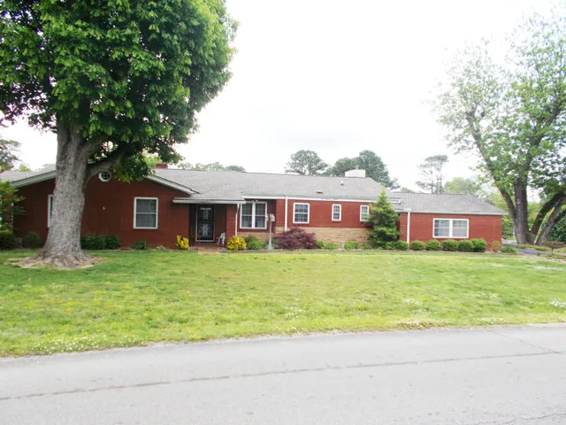 a front view of a house with a garden and trees