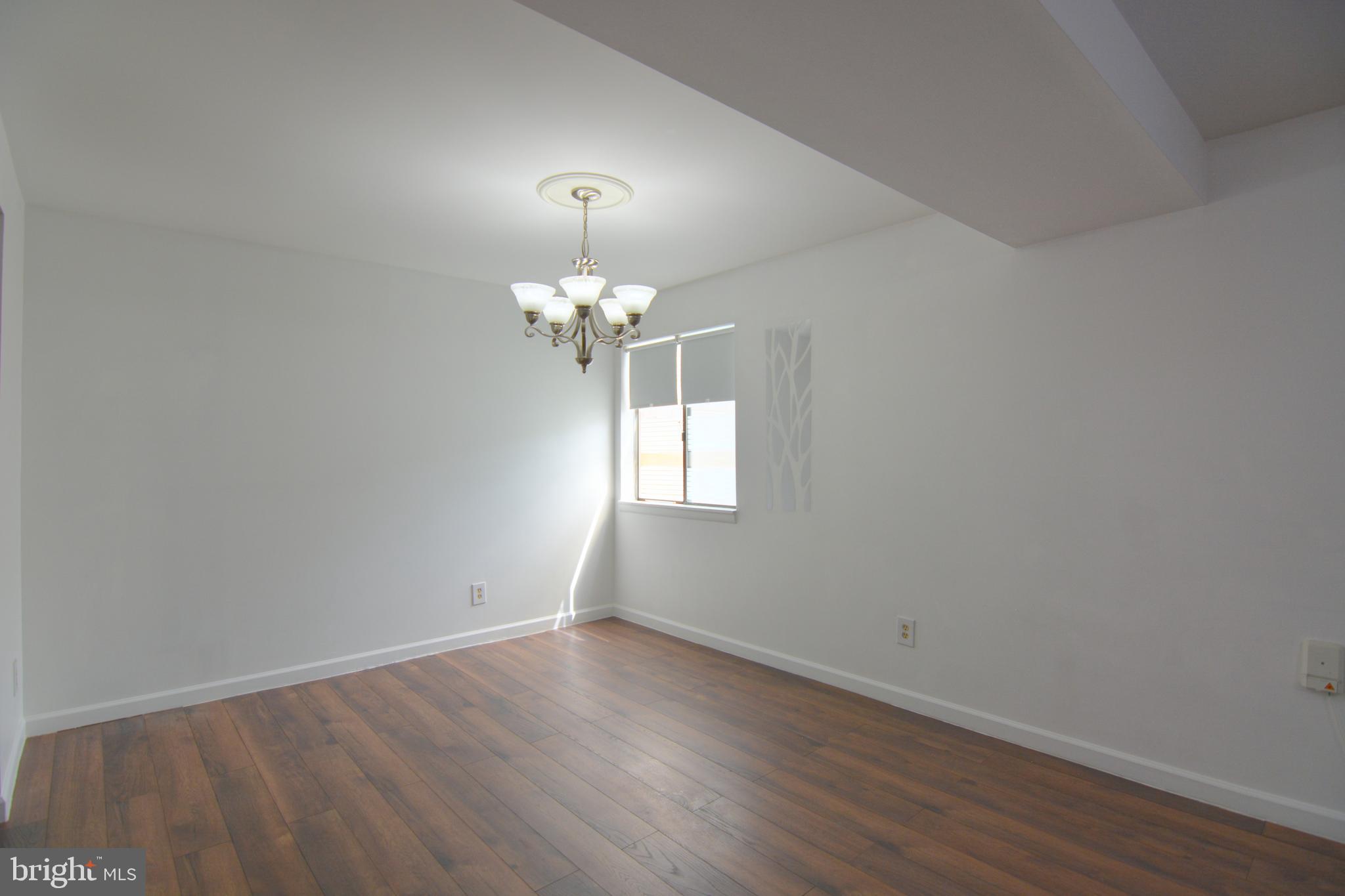 18905 Smoothstone Way, Unit I3 Gaithersburg, MD 20886 - Photo 12 of 32 an empty room with wooden floor and chandelier