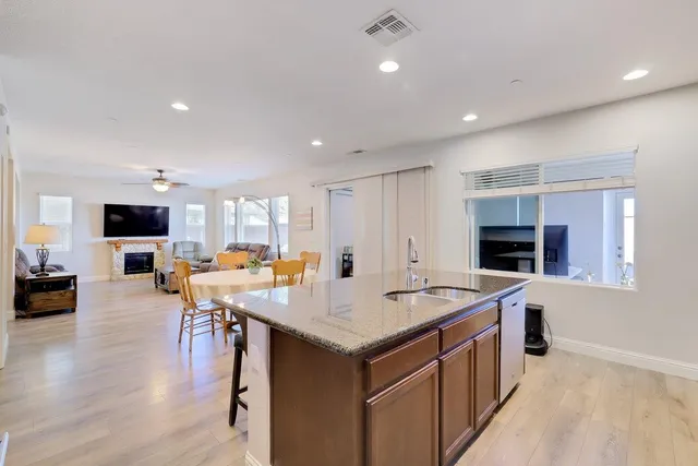 a kitchen with stainless steel appliances granite countertop a refrigerator a stove and a sink with wooden floor